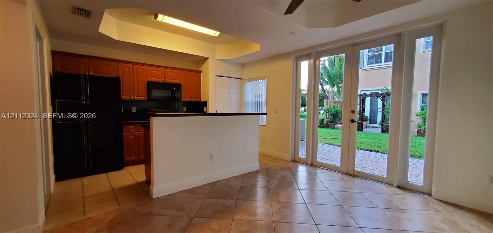 Kitchen featuring wood cabinetry, integrated black appliances, recessed lighting, tile flooring, and glass-paneled exterior doors