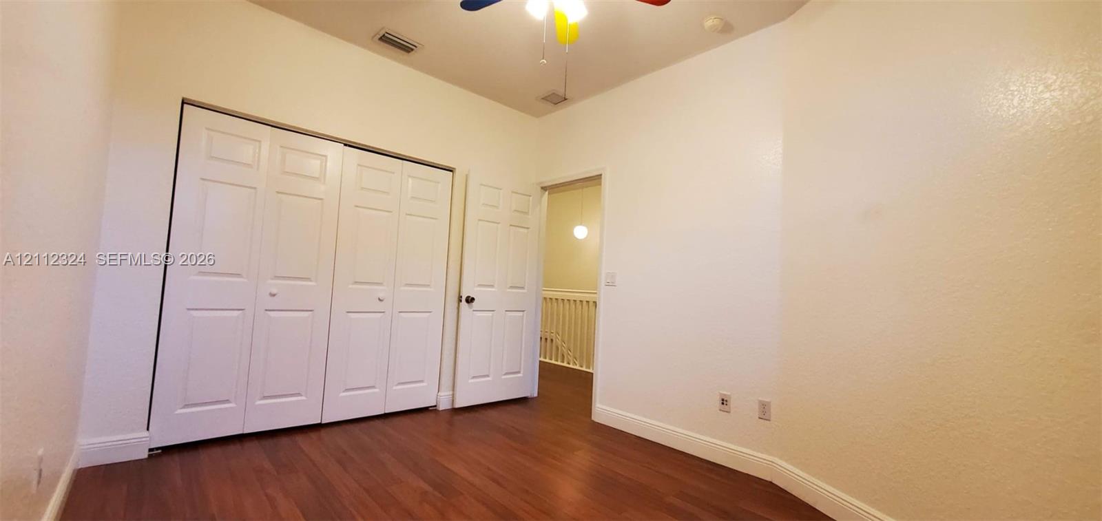 Wood-finish flooring, double-panel bifold closet doors, and six-panel interior door
