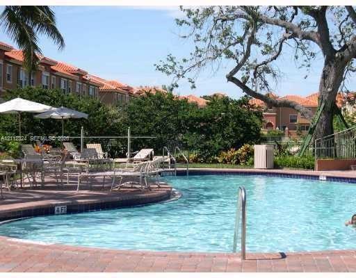 Curved swimming pool featuring a brick-paved deck and perimeter metal fencing