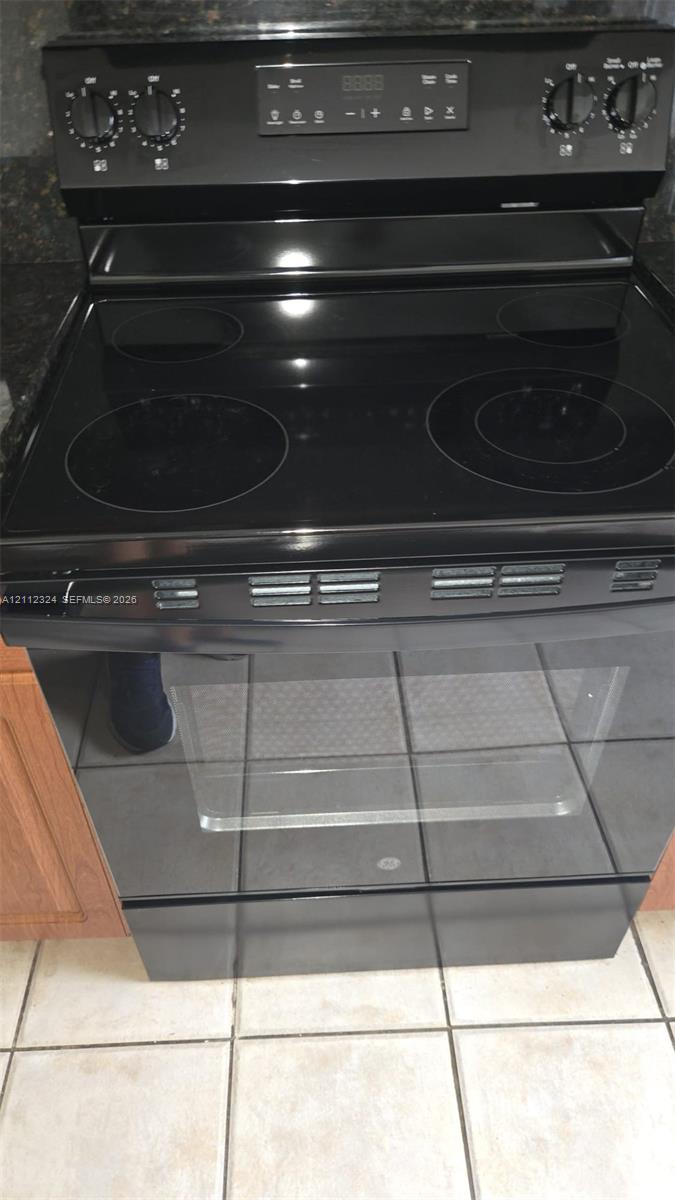 Black electric range featuring a smooth glass cooktop, digital control panel, and a large-capacity oven
