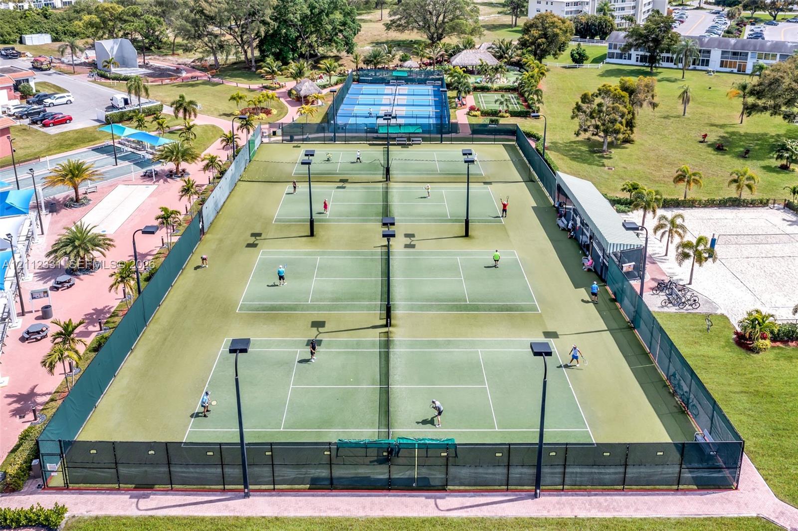 Multi-court tennis facility featuring perimeter chain-link fencing, court lighting, and paved pathways