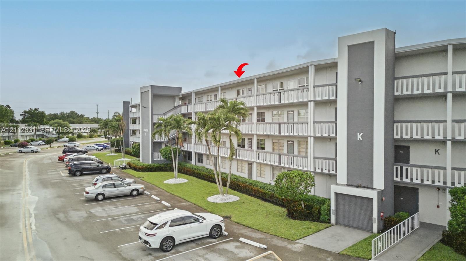 Mid-rise building featuring a concrete exterior with multi-level covered walkways and designated surface parking
