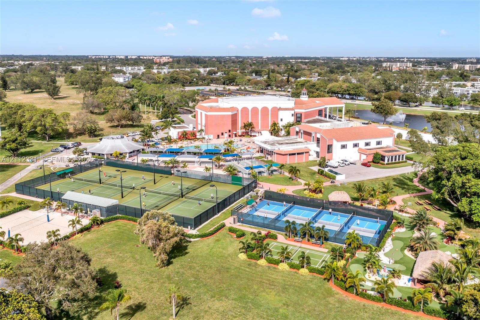Aerial perspective of a multi-facility recreational complex featuring multiple tennis courts, pickleball courts, a miniature golf course, and a swimming pool