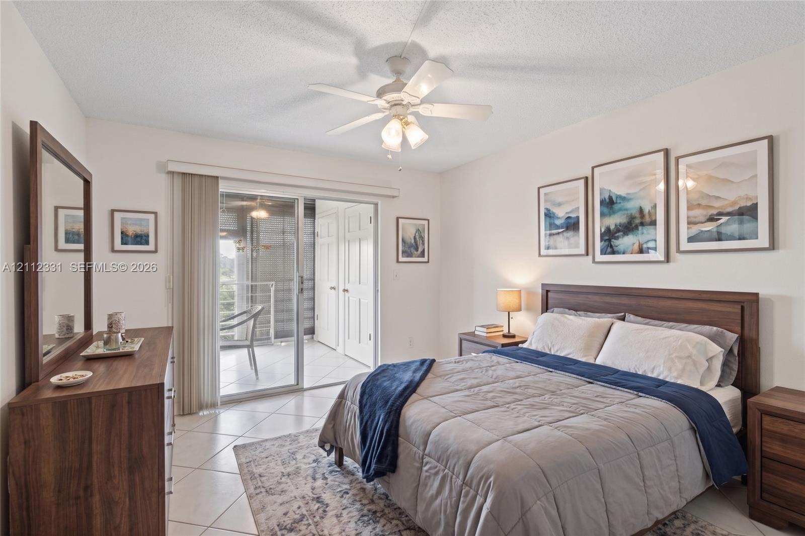 Neutral-toned tile flooring, white ceiling fan with integrated lighting, and glass sliding doors providing exterior access