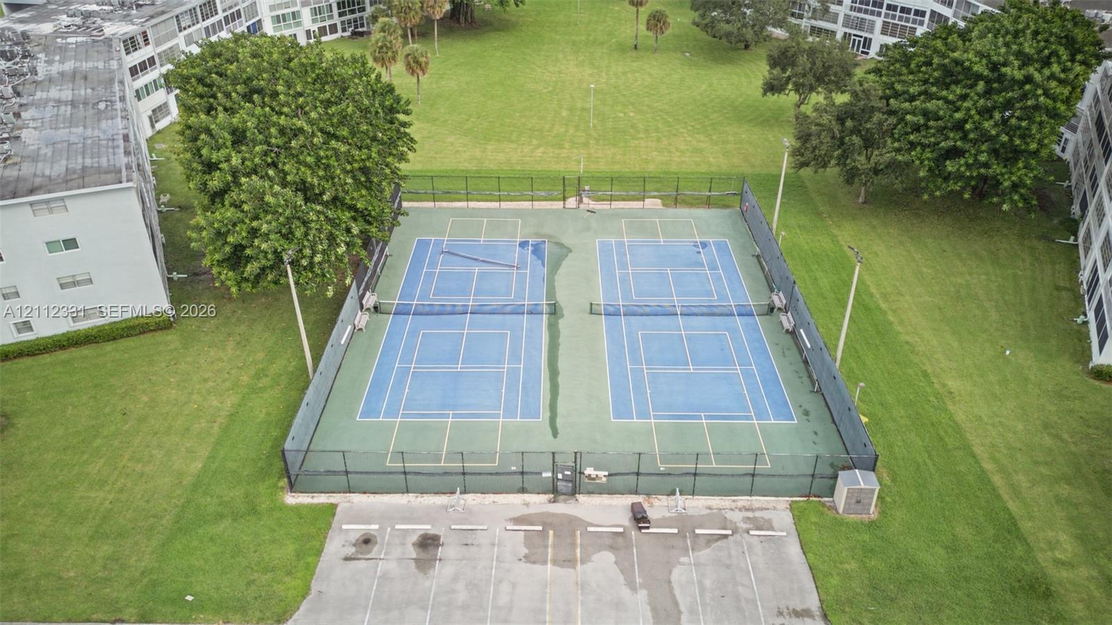 Dual tennis courts featuring hard-court surfaces, perimeter fencing, and integrated lighting