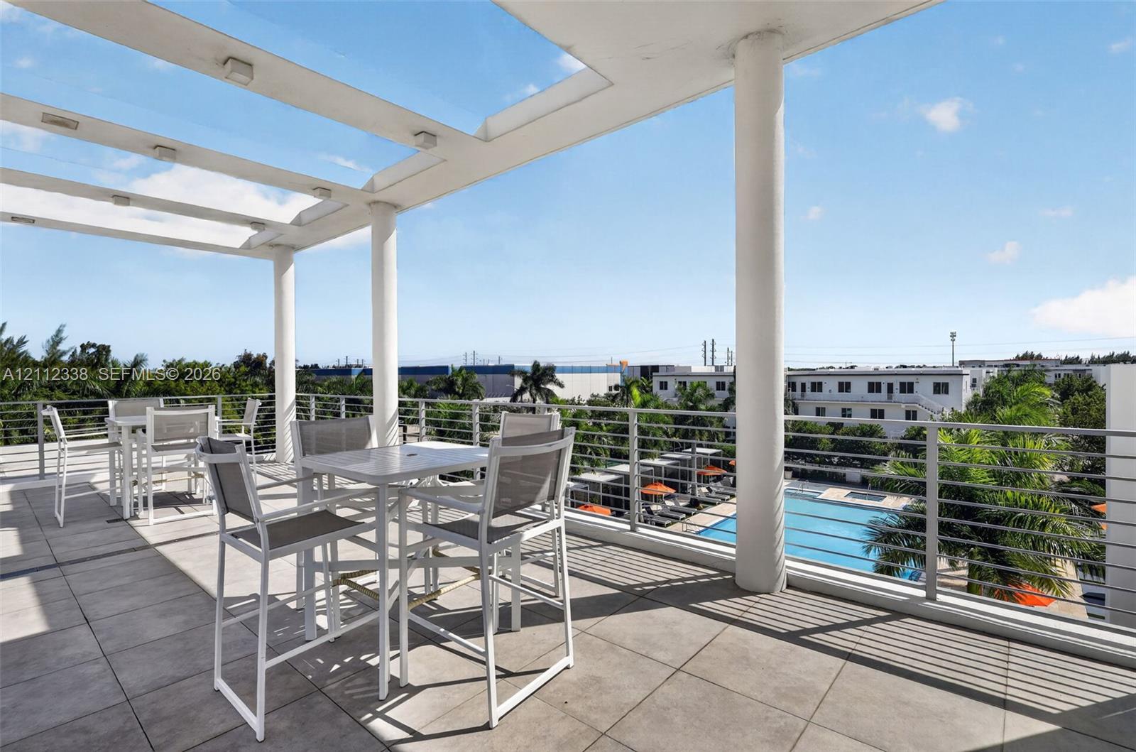 Covered terrace featuring large-format tile flooring, a glass-paneled pergola with integrated lighting, and a stainless steel cable railing system