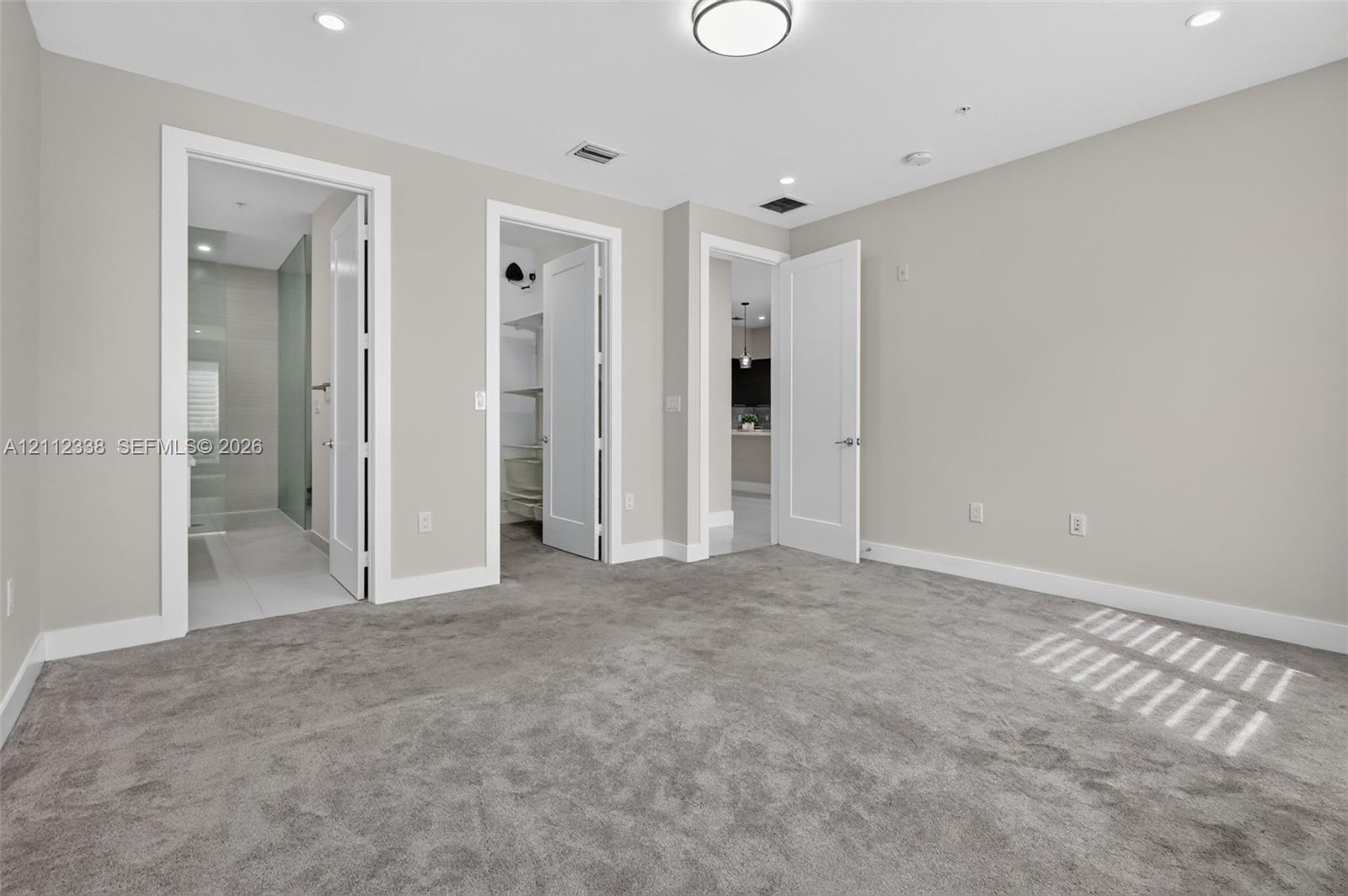 Interior room featuring neutral wall tones, plush wall-to-wall carpeting, recessed LED lighting, and multi-panel shaker-style interior doors