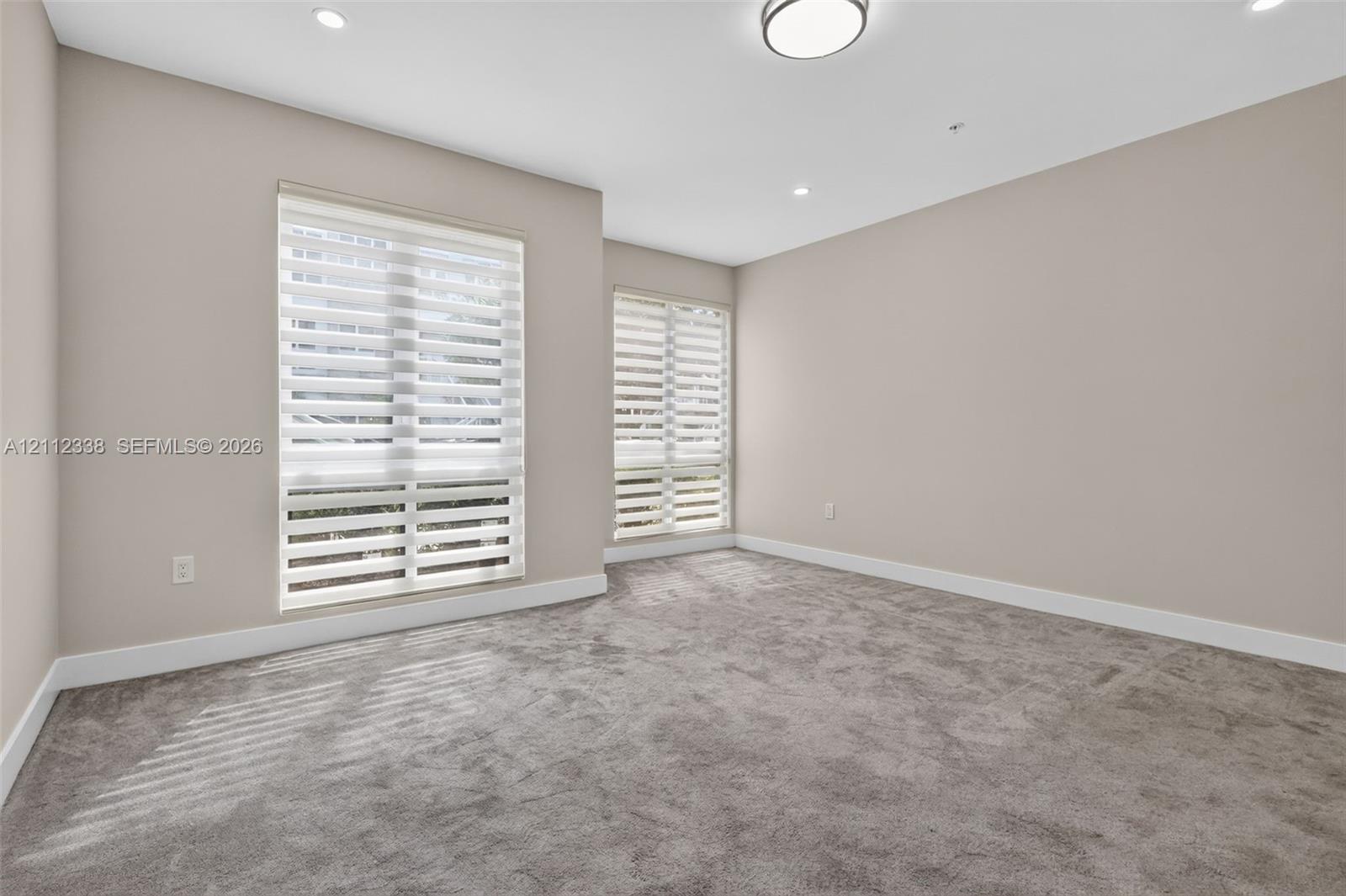 Neutral interior featuring wall-to-wall carpeting, recessed lighting, and dual windows equipped with roller shades