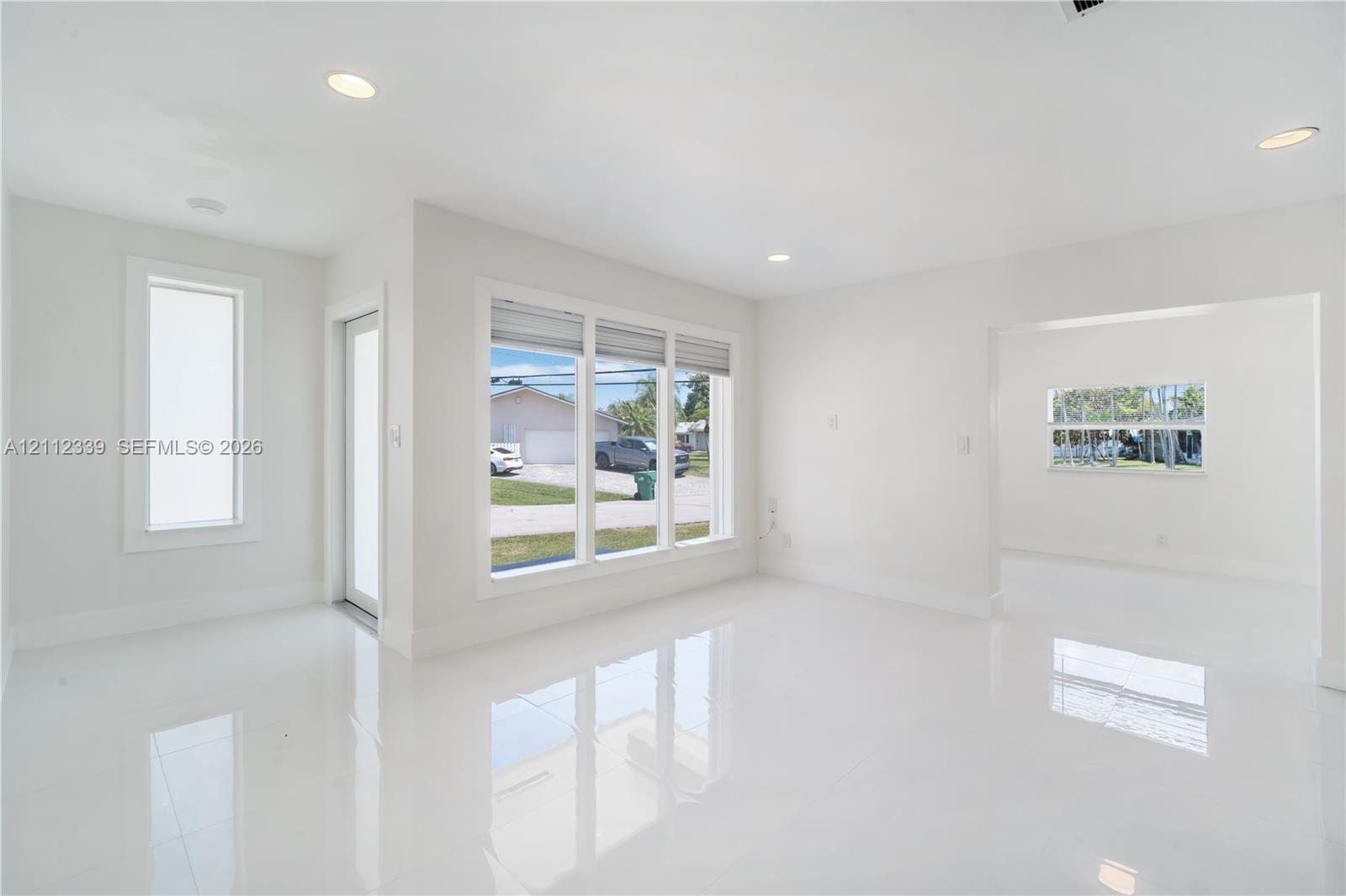 Large-format white tile flooring, recessed ceiling lighting, and expansive windows with natural light exposure