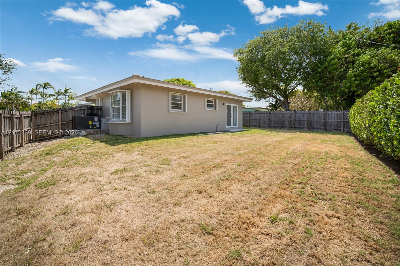 Backyard featuring a wood privacy fence, perimeter landscaping, and a new AC * Accordion shutters throughout *
