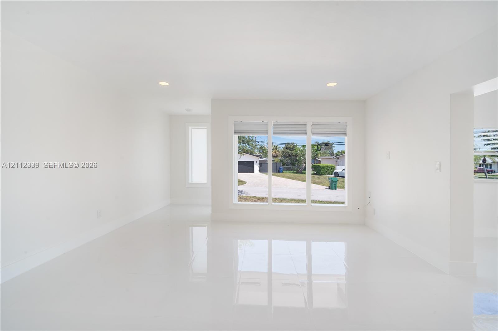 Open-concept interior featuring large-format polished tile flooring, recessed lighting, and a triple-pane picture window