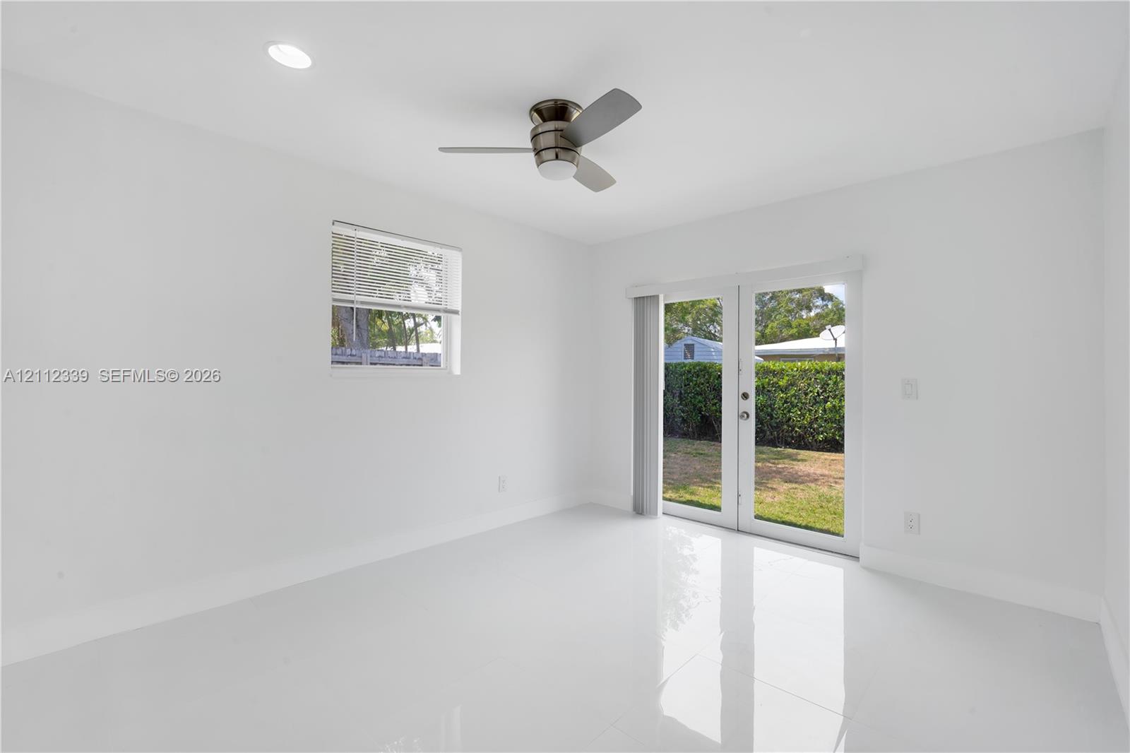 Glossy tile flooring, recessed lighting, ceiling fan, single-pane window, and glass-paned double doors leading to the backyard *