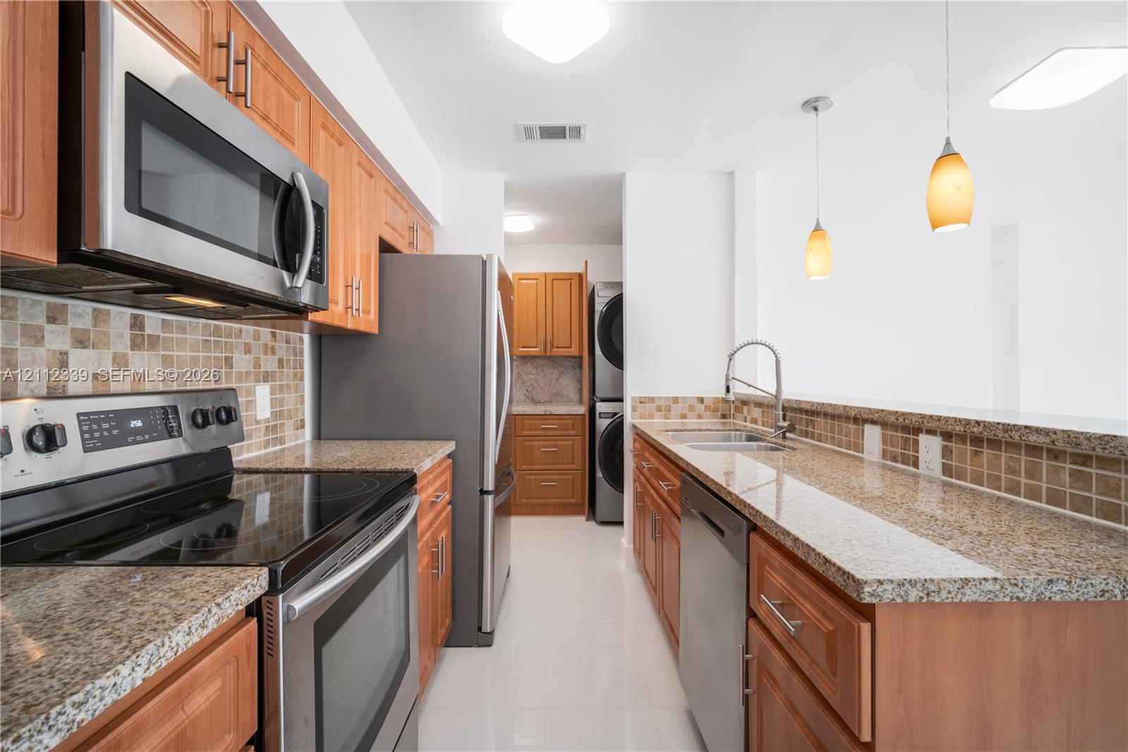 Kitchen featuring wood cabinetry, granite countertops, stainless steel appliances, tiled backsplash, and pendant lighting * Newer stainless steel appliances *