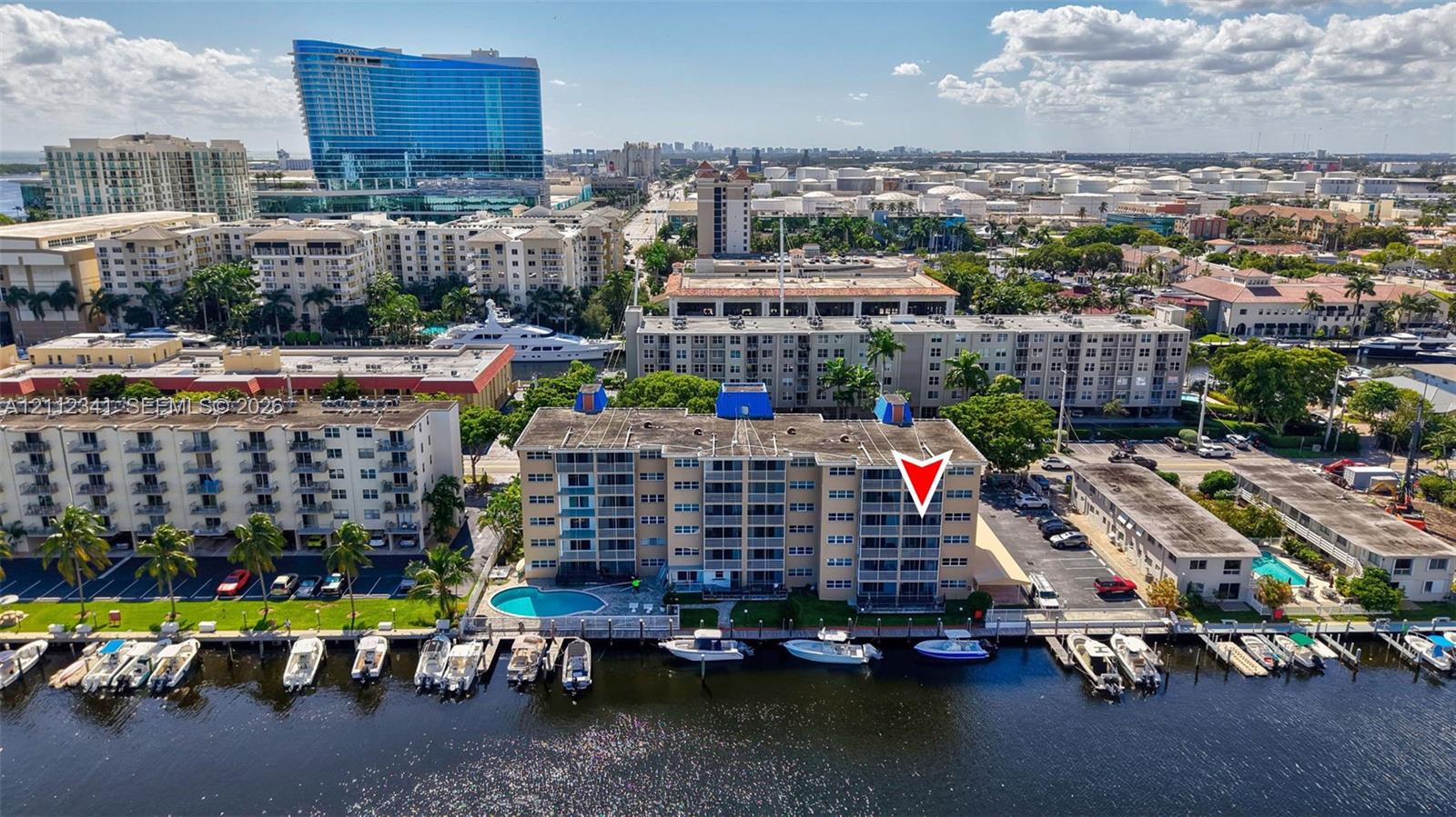 Mid-rise waterfront condominium featuring private boat slips, an outdoor swimming pool, and balconies