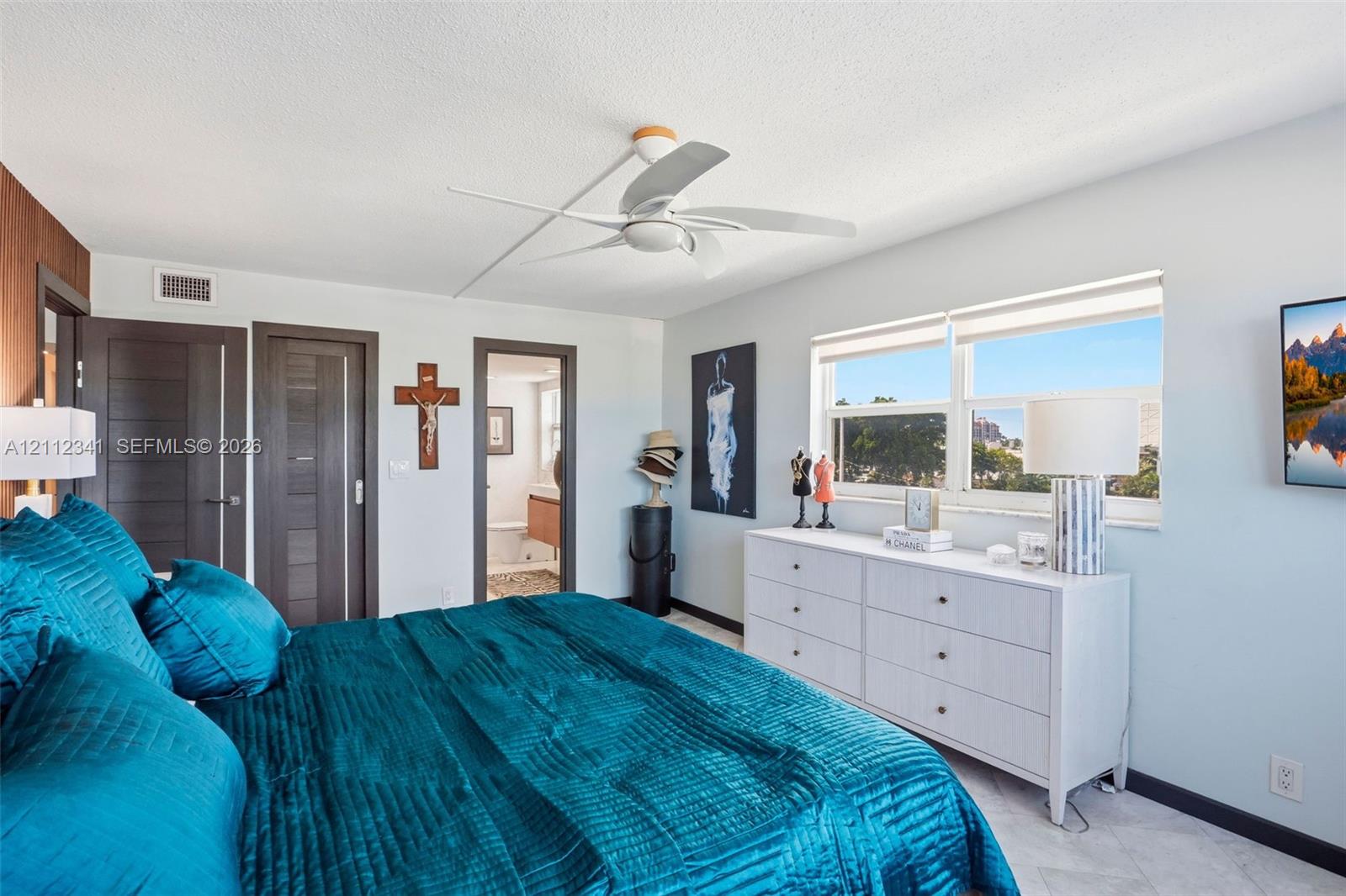 Bedroom featuring a multi-blade ceiling fan, wide-plank light-toned flooring, horizontal-panel interior doors, and oversized windows with light-filtering roller shades