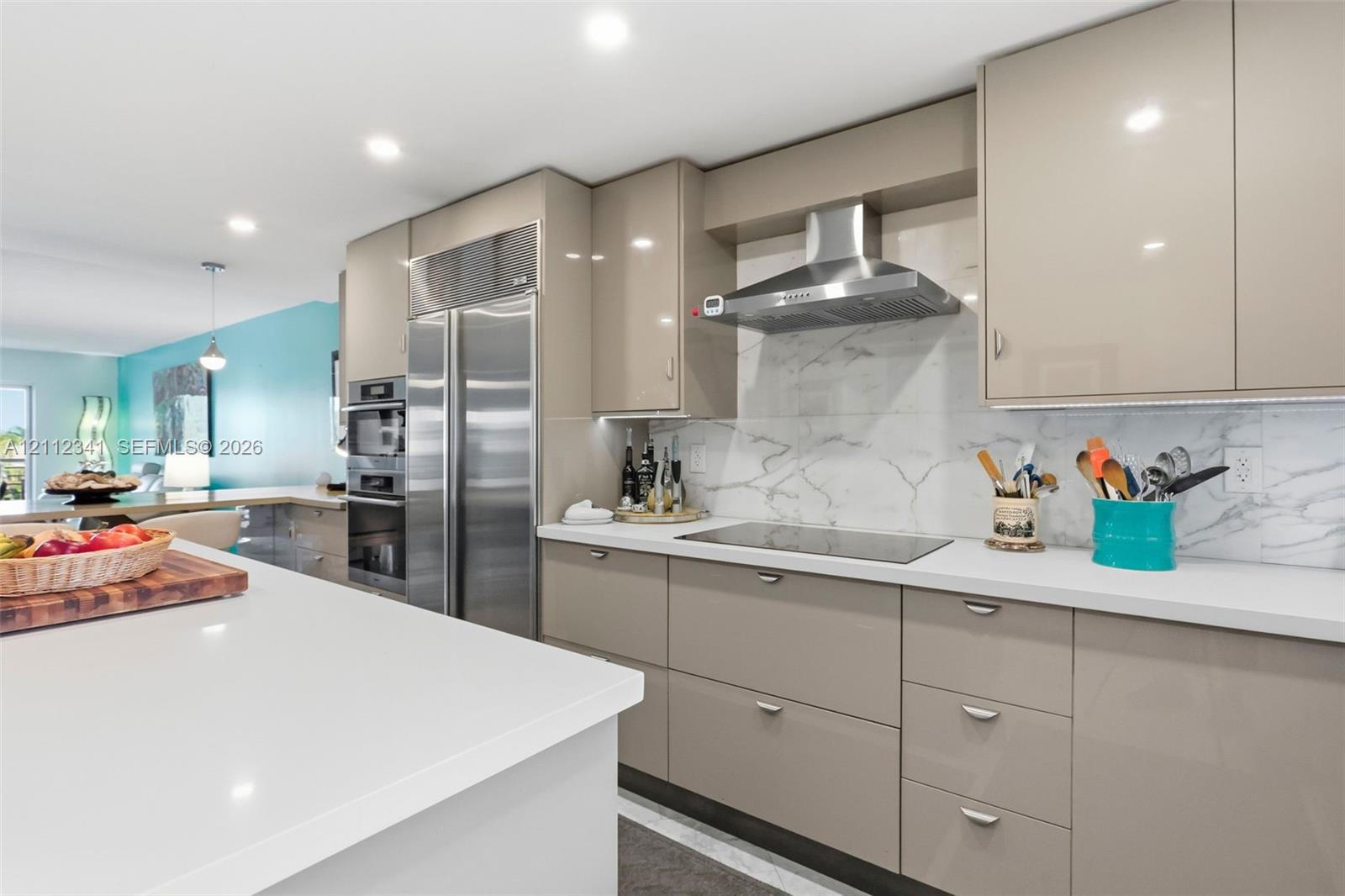 Kitchen featuring high-gloss cabinetry, stone-finish backsplash, quartz countertops, built-in stainless steel appliances, and recessed lighting
