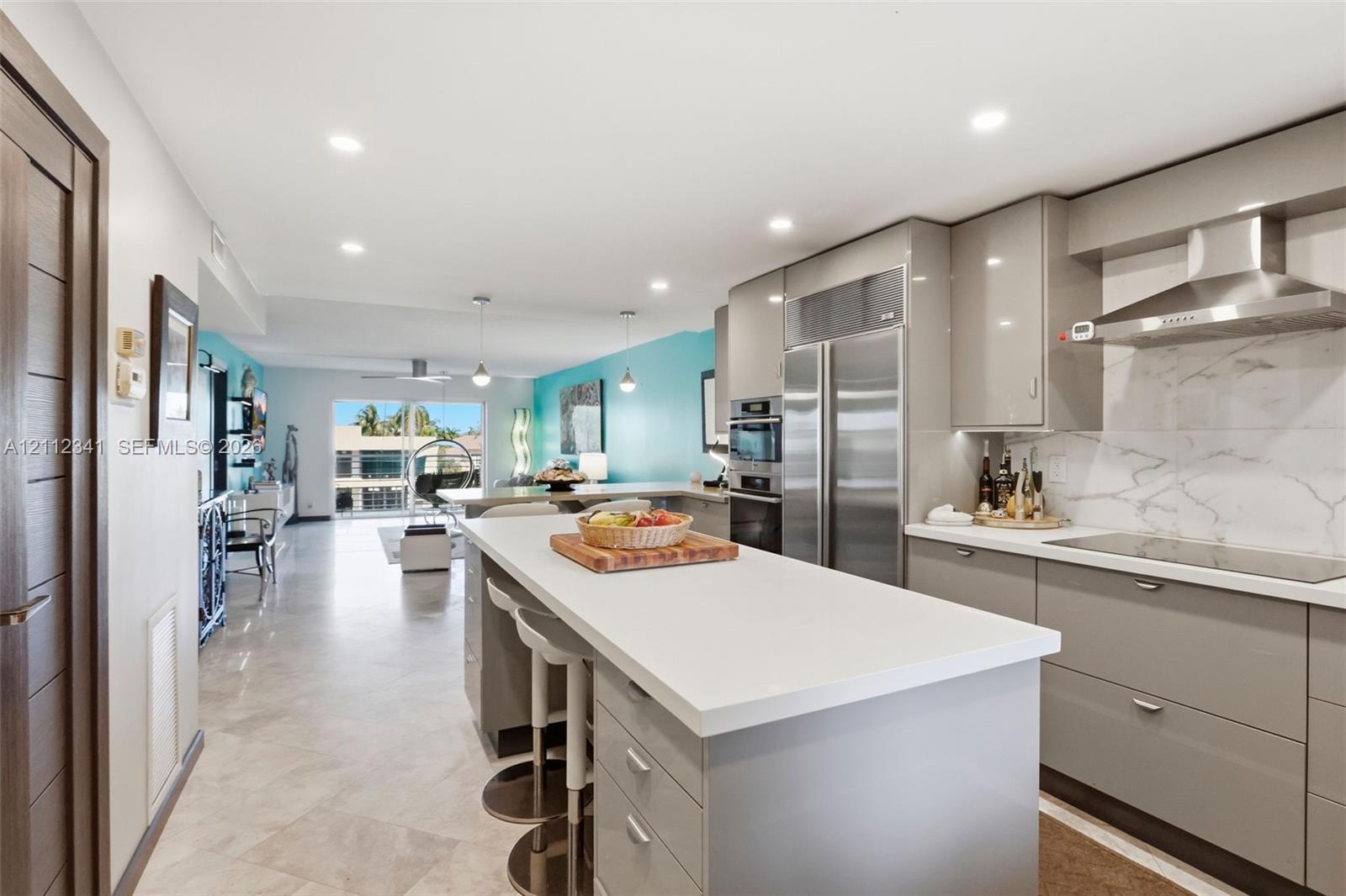 Modern kitchen featuring slab-front cabinetry, stone-surface countertops, a large center island, stainless steel appliances, and integrated recessed lighting