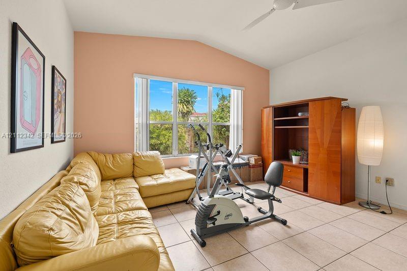 Vaulted ceiling, ceramic tile flooring, built-in wooden cabinetry, and large multi-pane windows