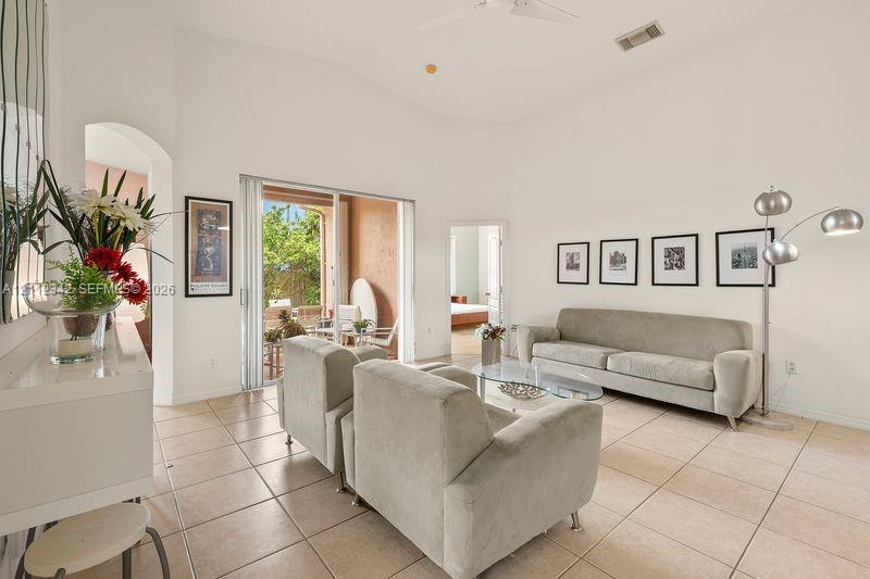Living area featuring vaulted ceilings, tile flooring, and sliding glass doors providing outdoor access