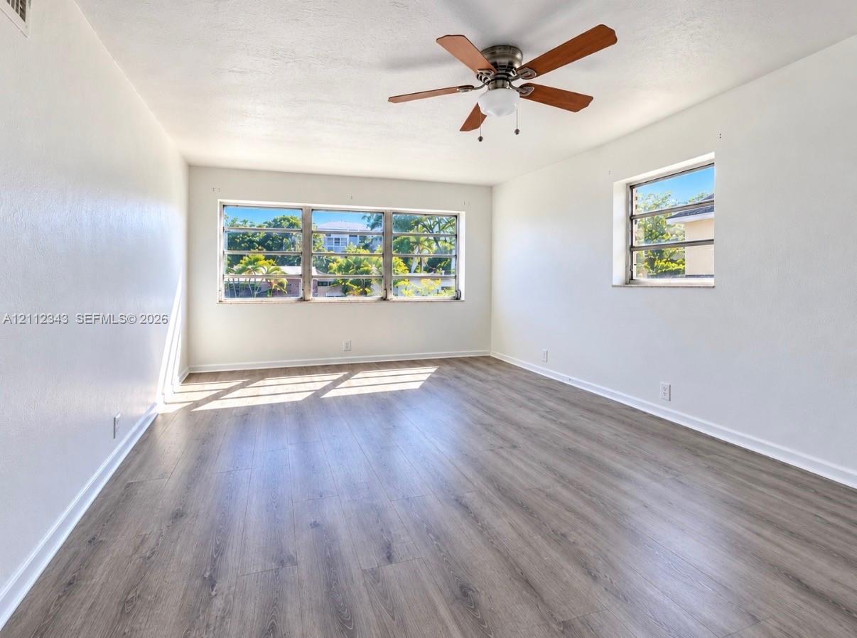 Wood-finish flooring, large multi-pane windows, and a ceiling-mounted fan with integrated lighting Wood-finish flooring, large multi-pane windows, and a ceiling-mounted fan with integrated lighting