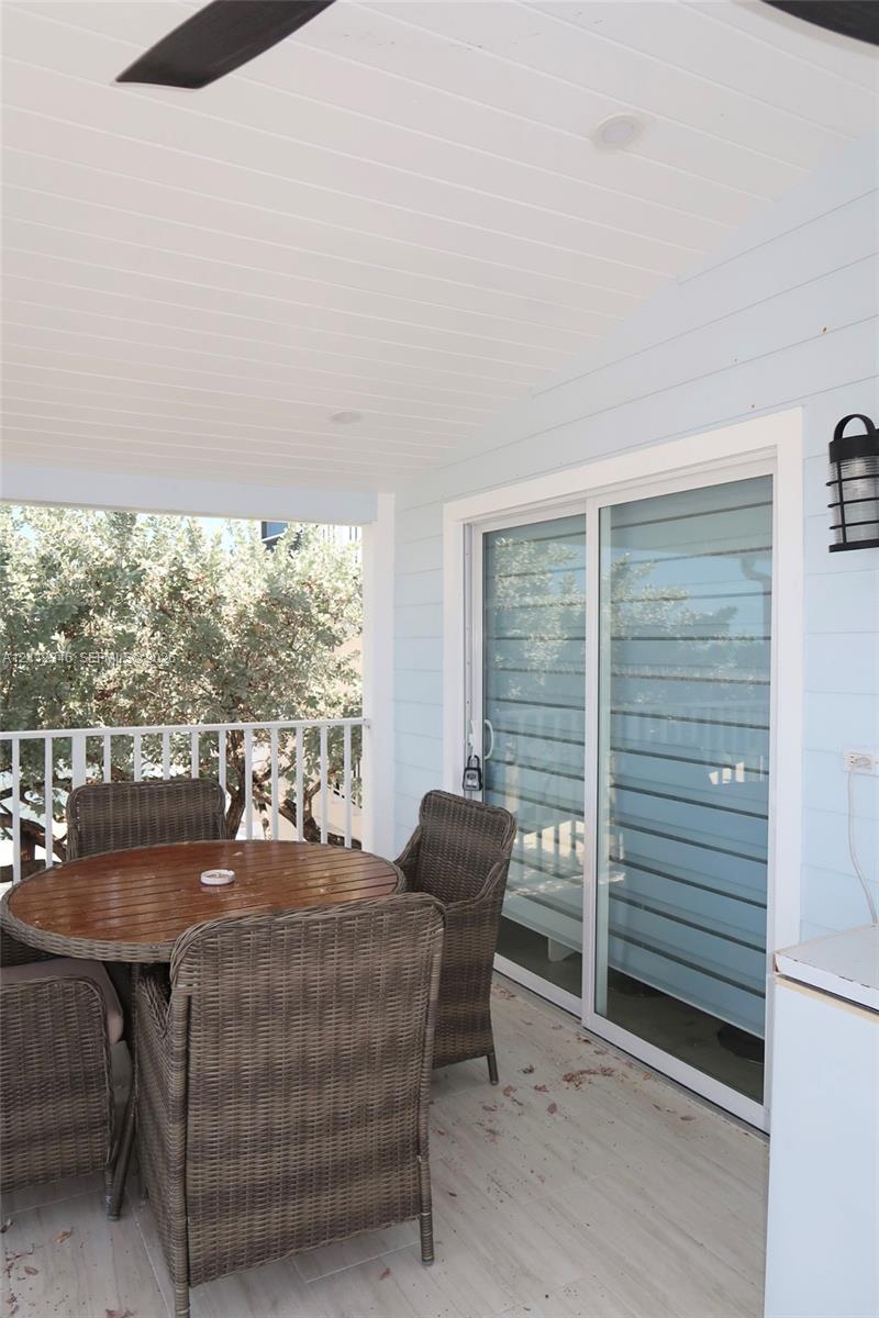 Covered balcony featuring beadboard ceiling, white metal railing, and direct water exposure with a private dock