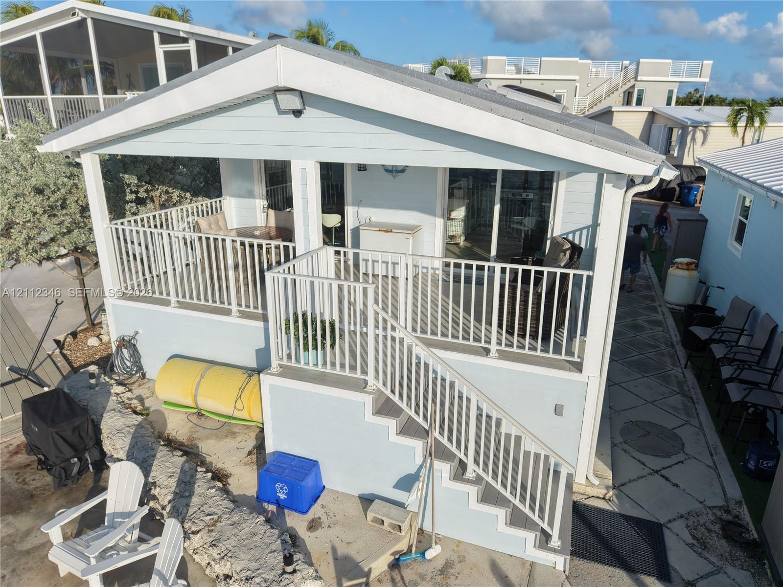 Light blue elevated home featuring a covered porch, white metal railing, and staircase