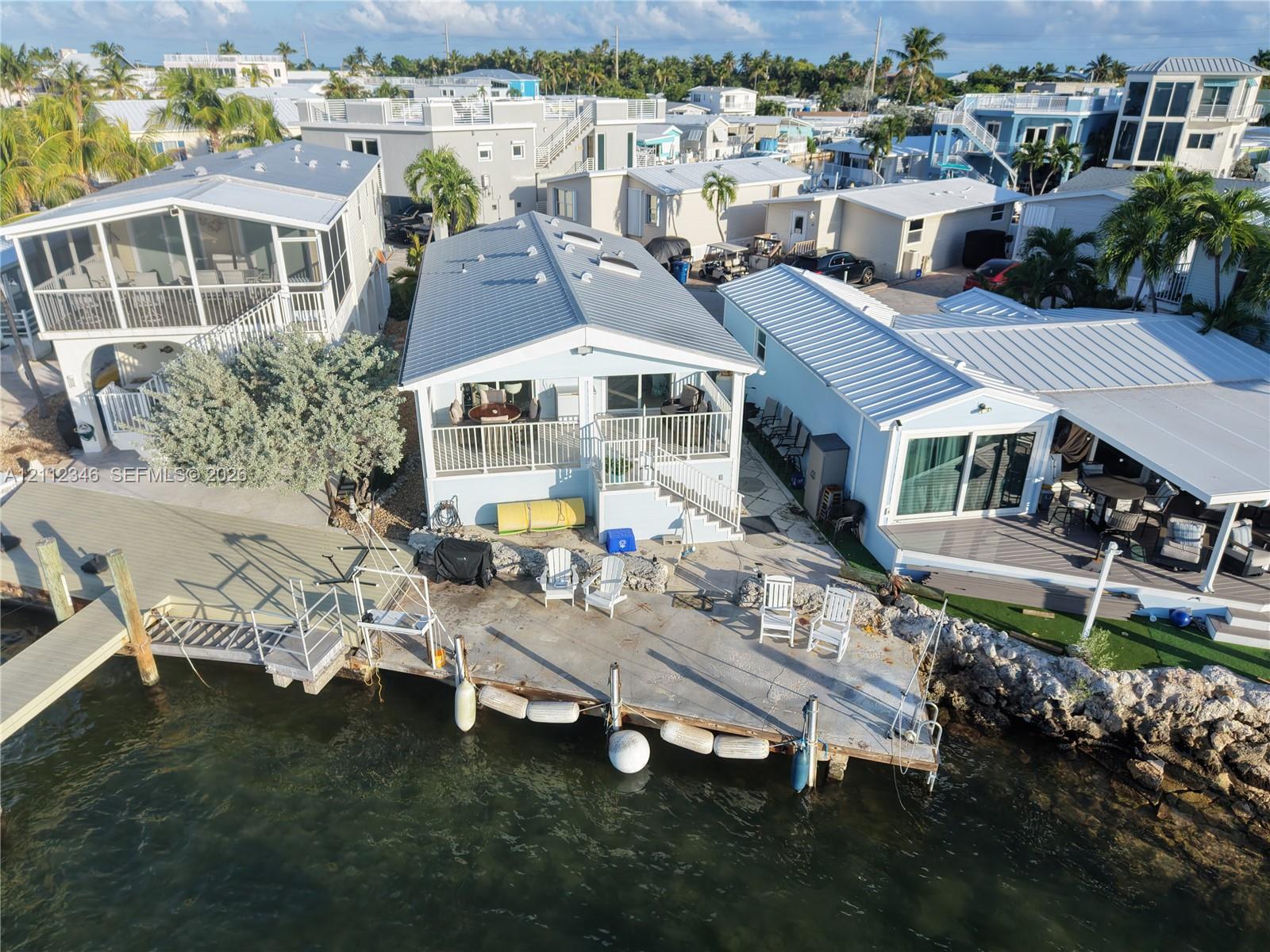 Waterfront residence featuring a metal roof, skylights, raised balcony with metal railings, and a concrete bulkhead with an attached private dock Waterfront residence featuring a metal roof, skylights, raised balcony with metal railings, and a concrete bulkhead with an attached private dock