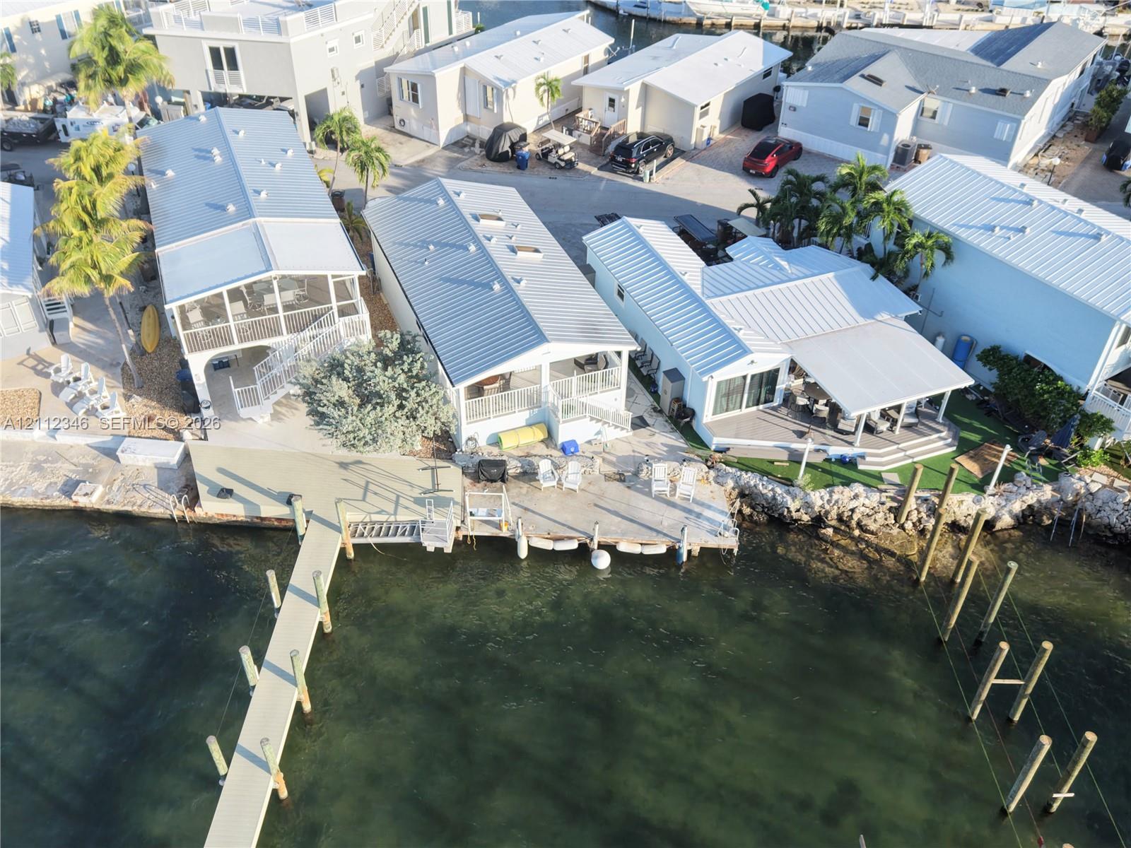 Waterfront property featuring a private boat dock, multi-level exterior decking, metal roof systems, and reinforced seawall