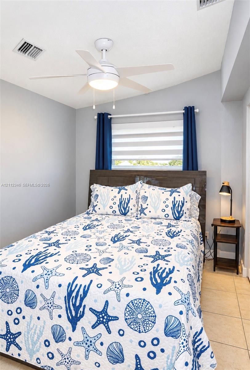 Ceiling-mounted fan with integrated light fixture, horizontal blind window treatment, and neutral tile flooring Ceiling-mounted fan with integrated light fixture, horizontal blind window treatment, and neutral tile flooring