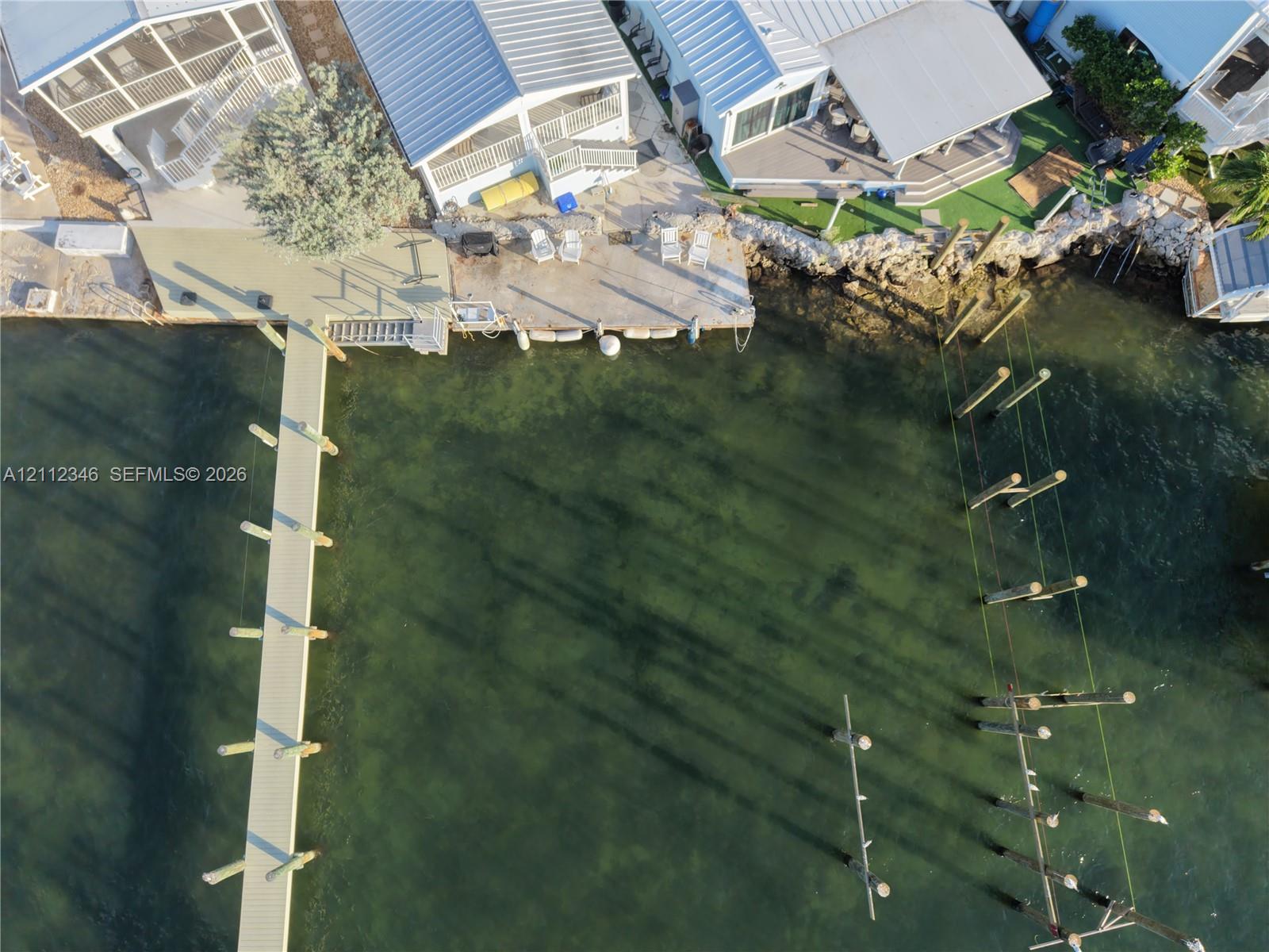 Waterfront property featuring a private boat dock, extended pier, bulkhead hardscaping, and metal roofing Waterfront property featuring a private boat dock, extended pier, bulkhead hardscaping, and metal roofing