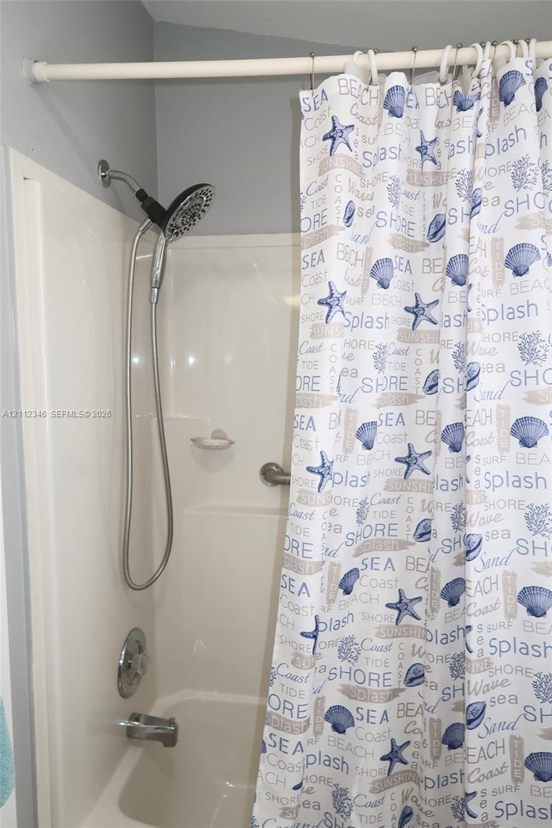 Bathtub and shower combination with a molded composite surround, integrated soap dish, chrome-finished multi-setting handheld shower head, and chrome diverter valve