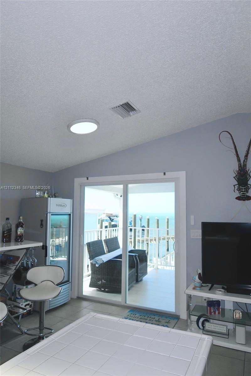 Sloped ceiling with recessed lighting and sliding glass doors opening to a waterfront balcony Sloped ceiling with recessed lighting and sliding glass doors opening to a waterfront balcony