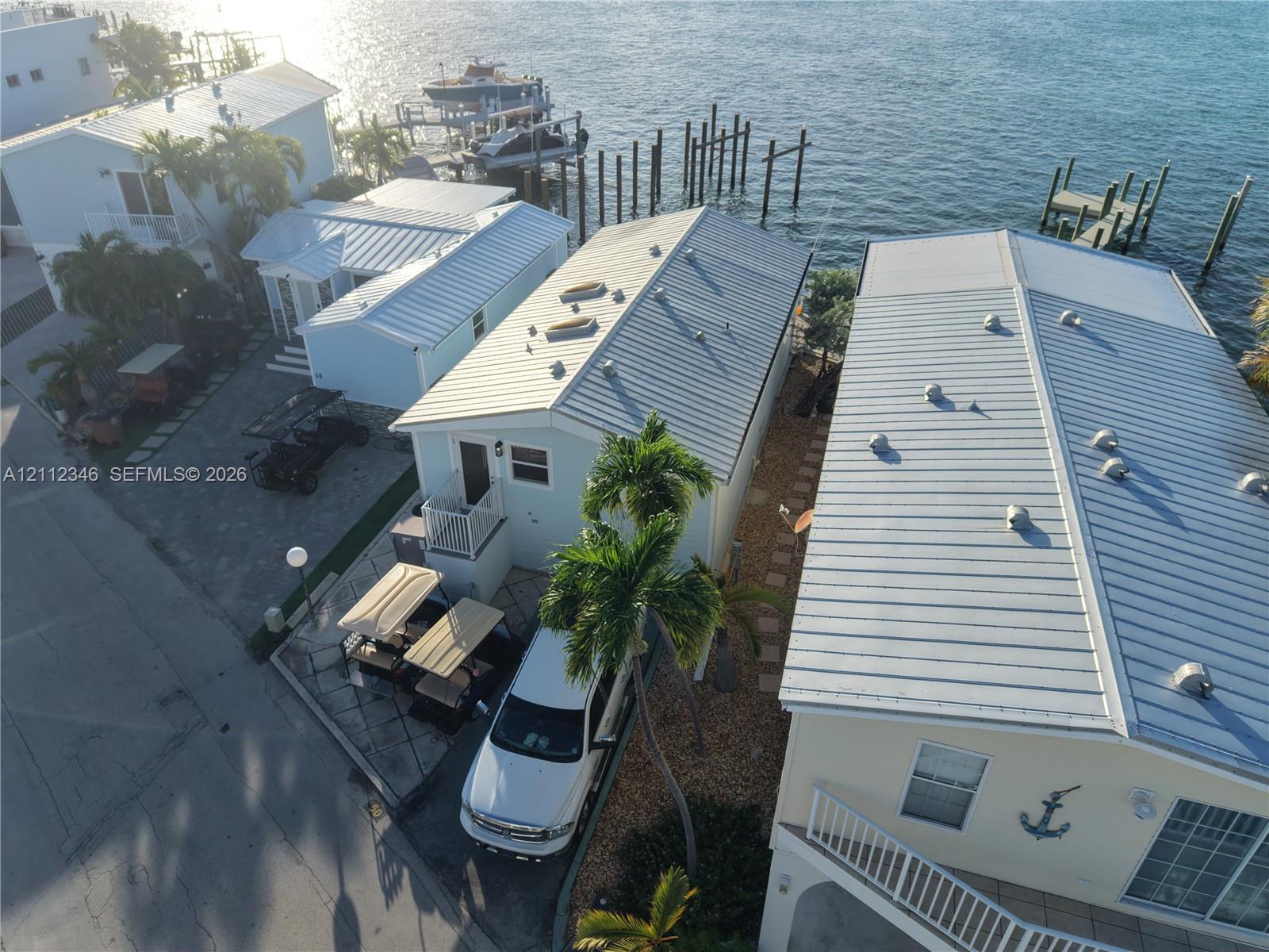 Waterfront property featuring metal roofing, private boat slip, paved driveway, and elevated exterior staircase