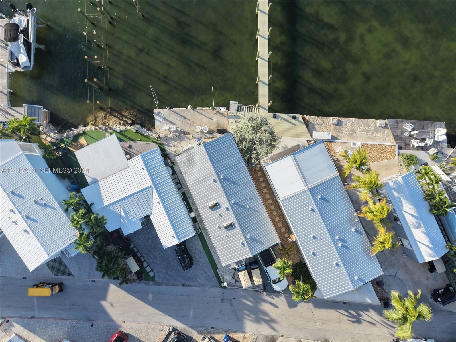 Waterfront property featuring metal roofing, a private dock, and paved hardscaping