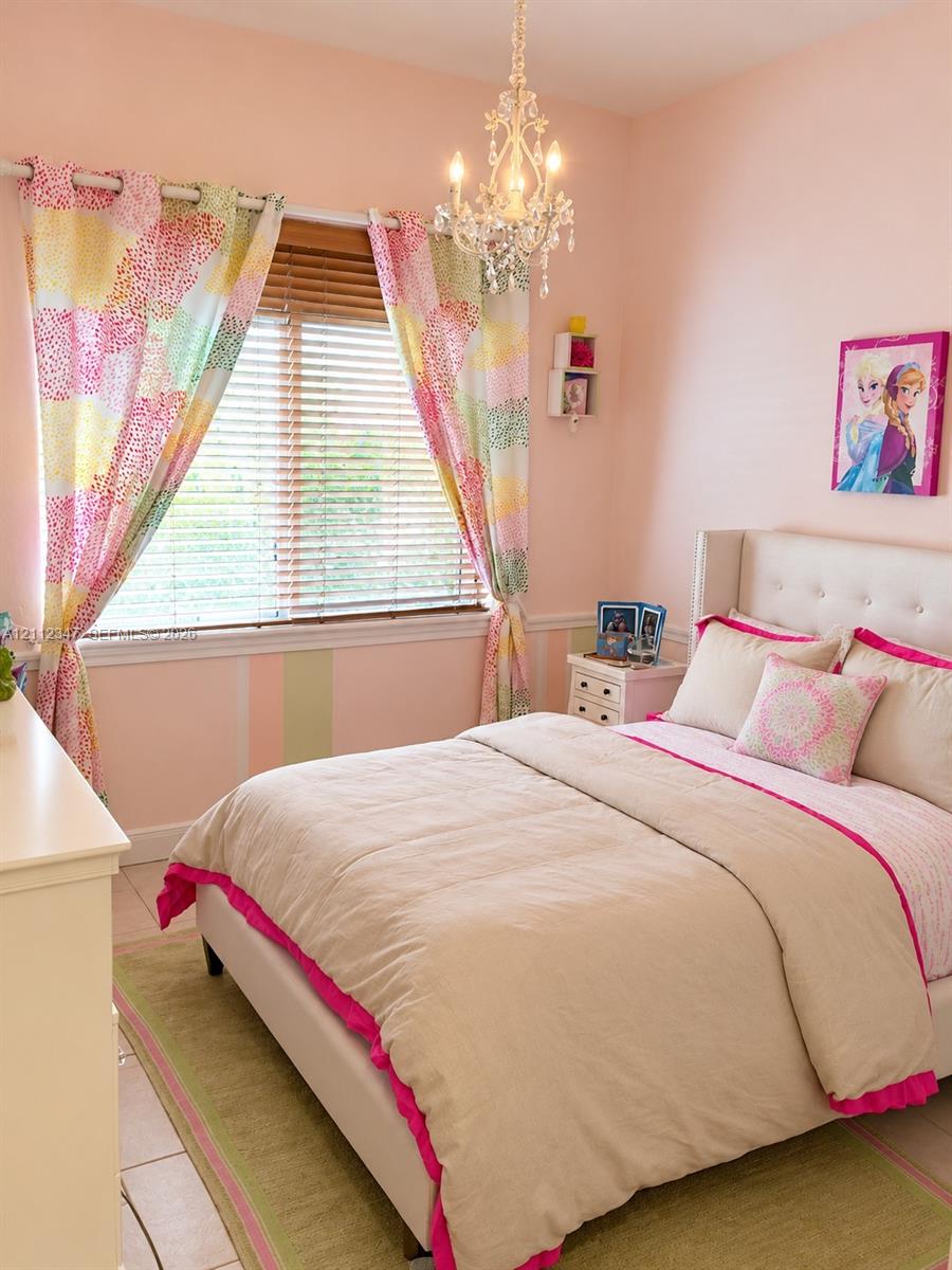 Bedroom featuring a crystal-style chandelier, horizontal window blinds, and tile flooring