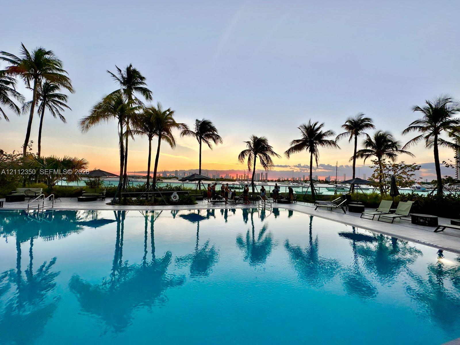 Swimming pool featuring a paved perimeter, integrated entry steps, and mature palm trees