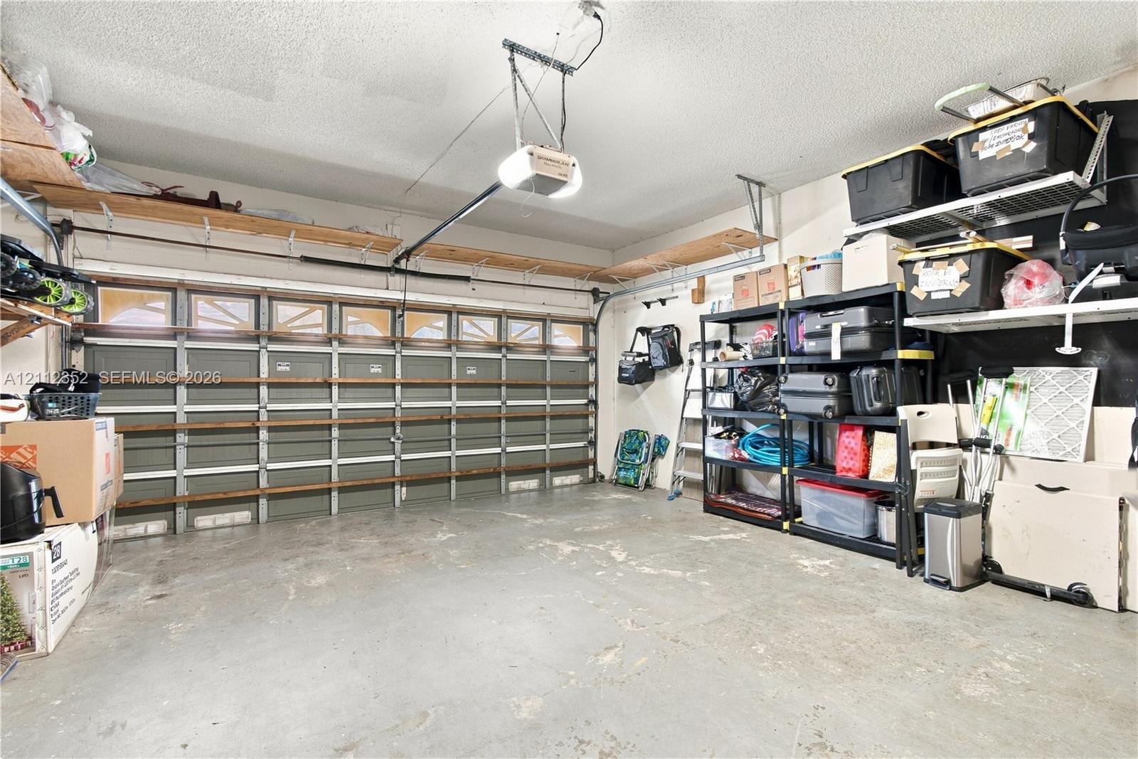 Multi-car garage featuring a sectional door with windows, integrated ceiling-mounted lighting, and extensive wall-mounted wood shelving