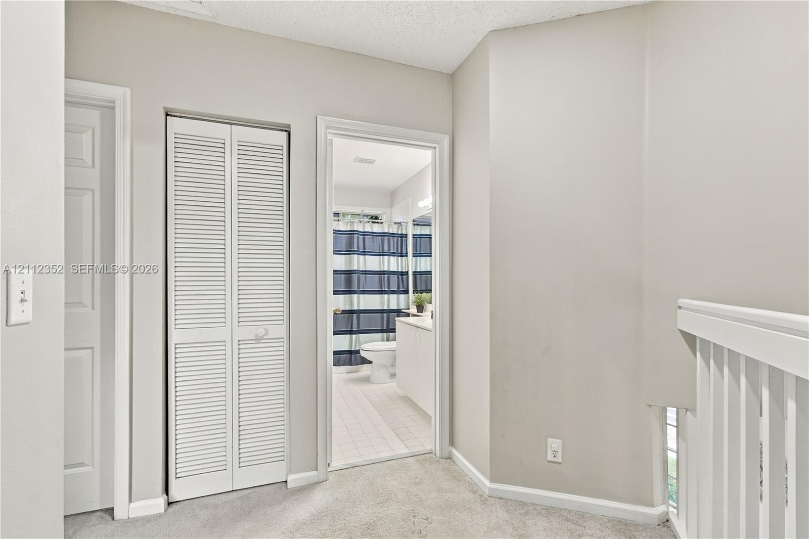 Neutral-toned interior featuring louvered bifold closet doors, white painted millwork, and carpeted flooring