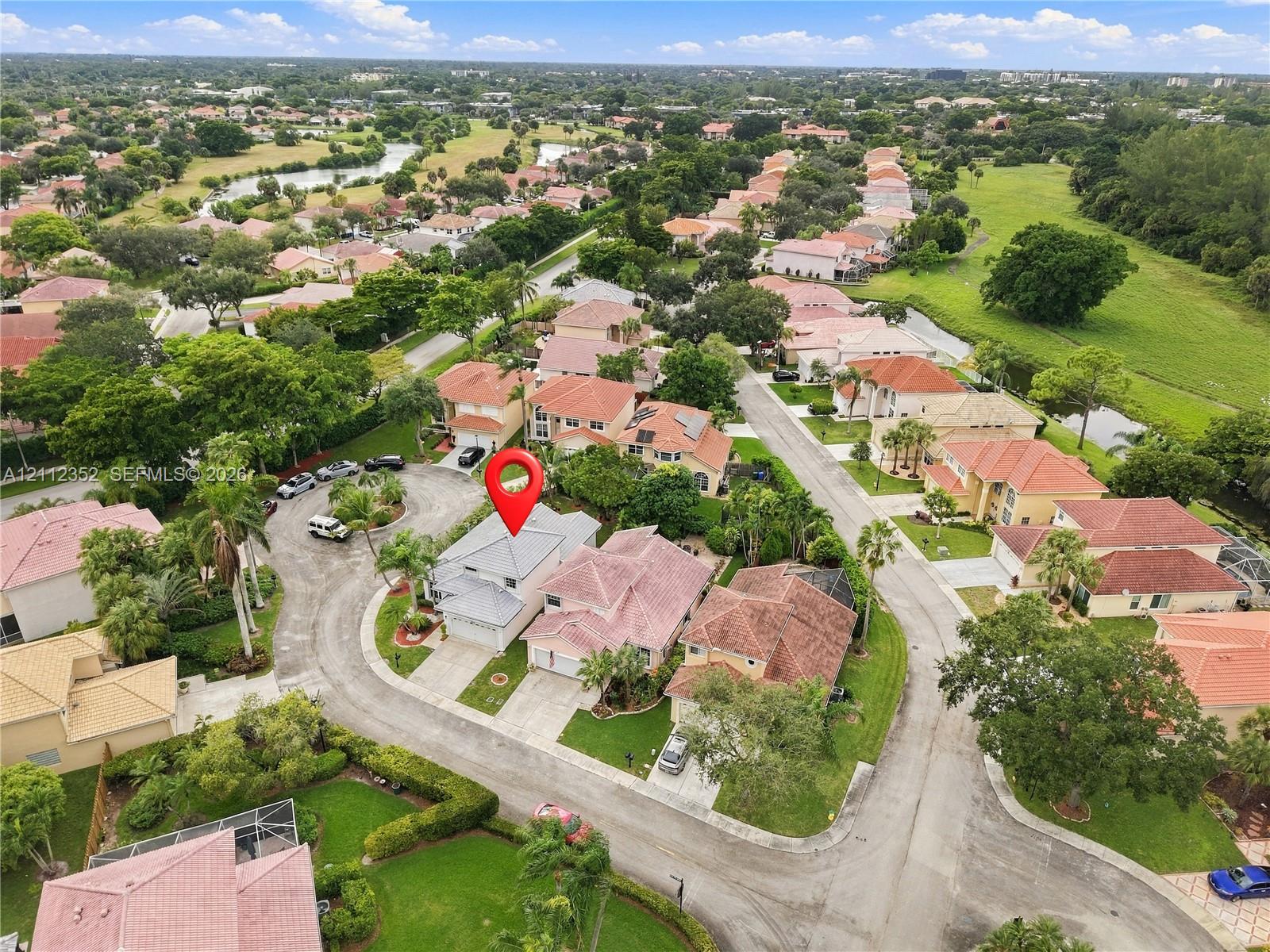 Aerial perspective of a single-family residence situated on a cul-de-sac within a residential community featuring extensive green space and water features