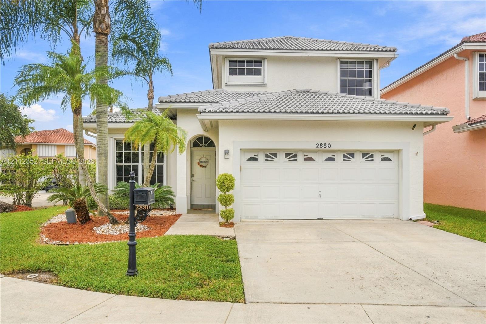 Two-story exterior featuring light-colored stucco siding, a tiled roof, multi-pane windows, and an attached two-car garage Two-story exterior featuring light-colored stucco siding, a tiled roof, multi-pane windows, and an attached two-car garage