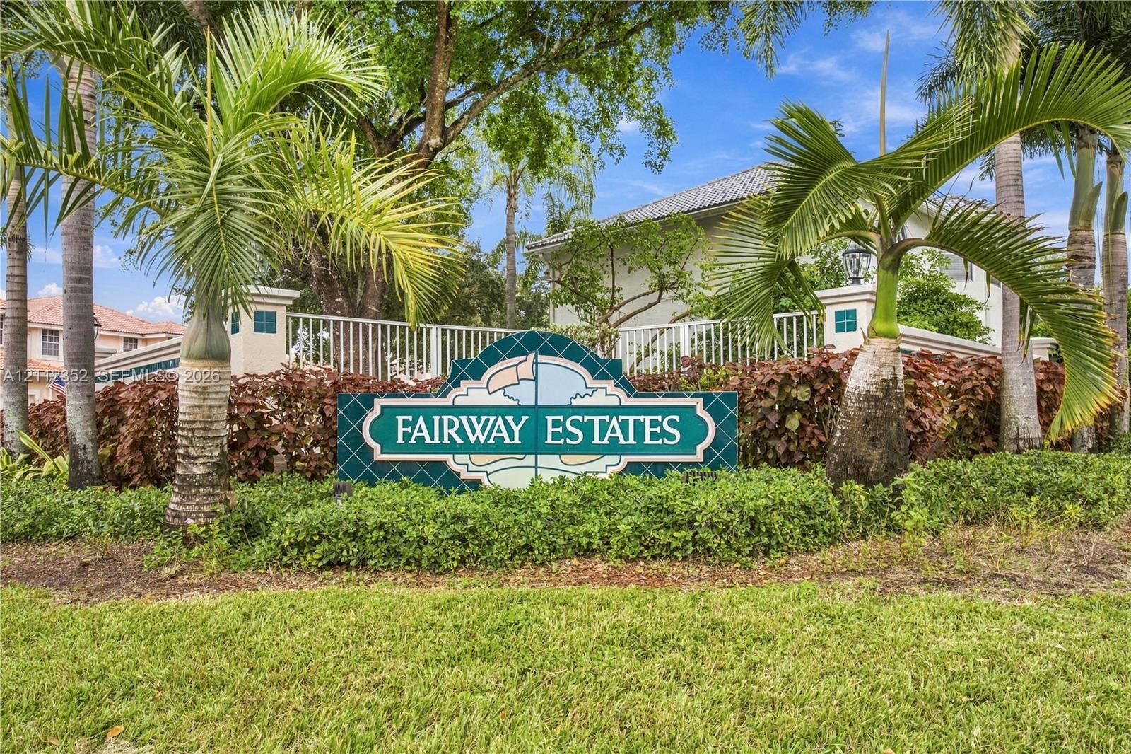 Community monument sign featuring decorative masonry, perimeter fencing, lush landscaping, and mature palms Community monument sign featuring decorative masonry, perimeter fencing, lush landscaping, and mature palms