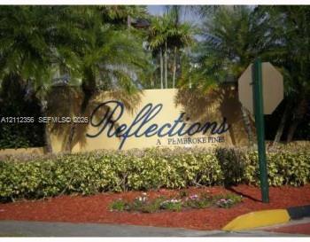 Reflections at Pembroke Pines monument signage featuring stucco wall construction, ornamental palm trees, and manicured shrubbery
