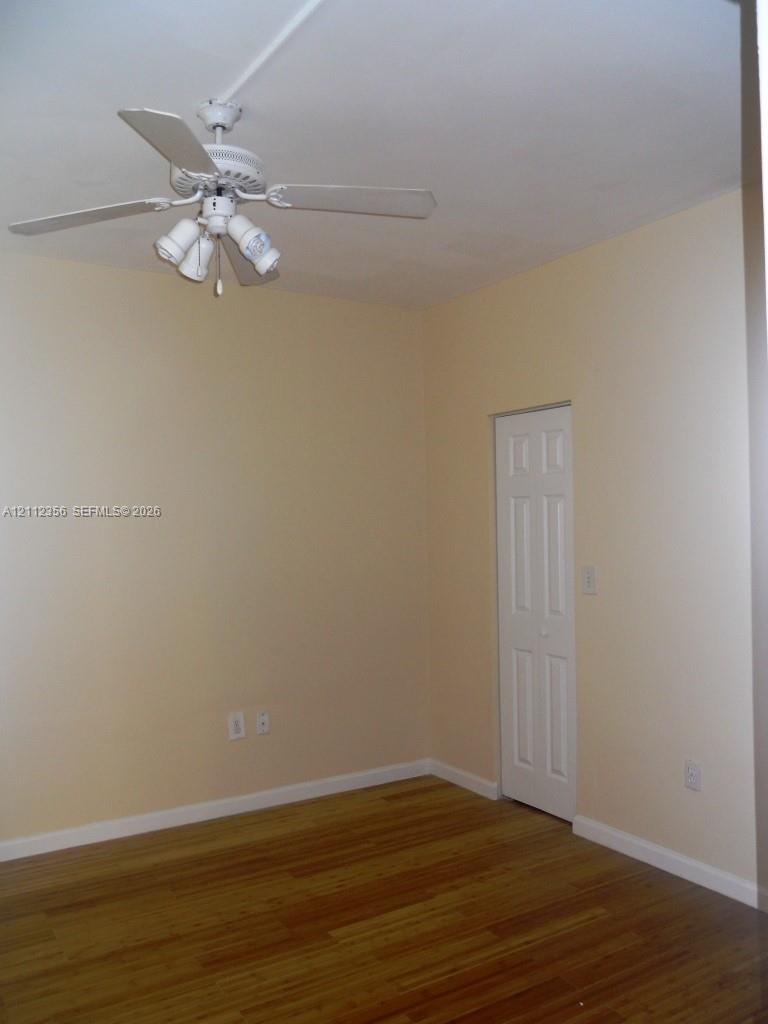 Room featuring wood-finish flooring, a white ceiling fan with integrated light fixture, and a white bi-fold closet door