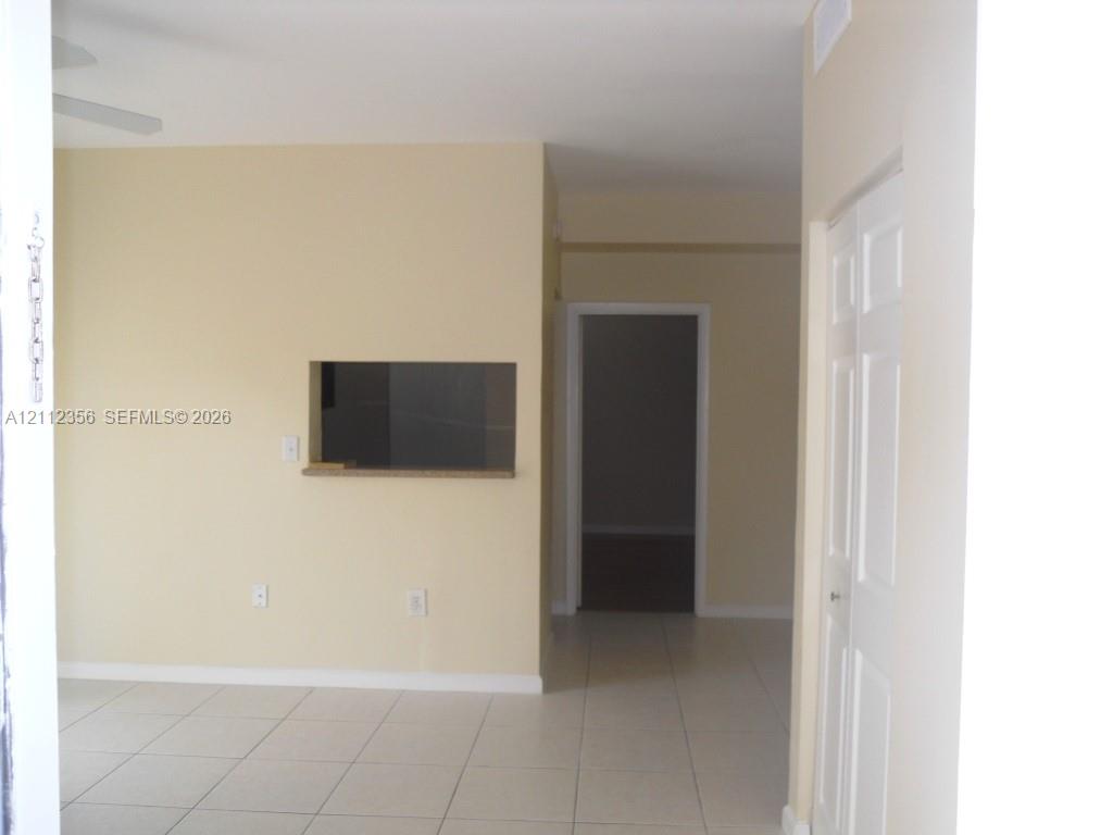 Neutral wall paint, light-toned ceramic tile flooring, and interior pass-through window with a stone-finish ledge Neutral wall paint, light-toned ceramic tile flooring, and interior pass-through window with a stone-finish ledge