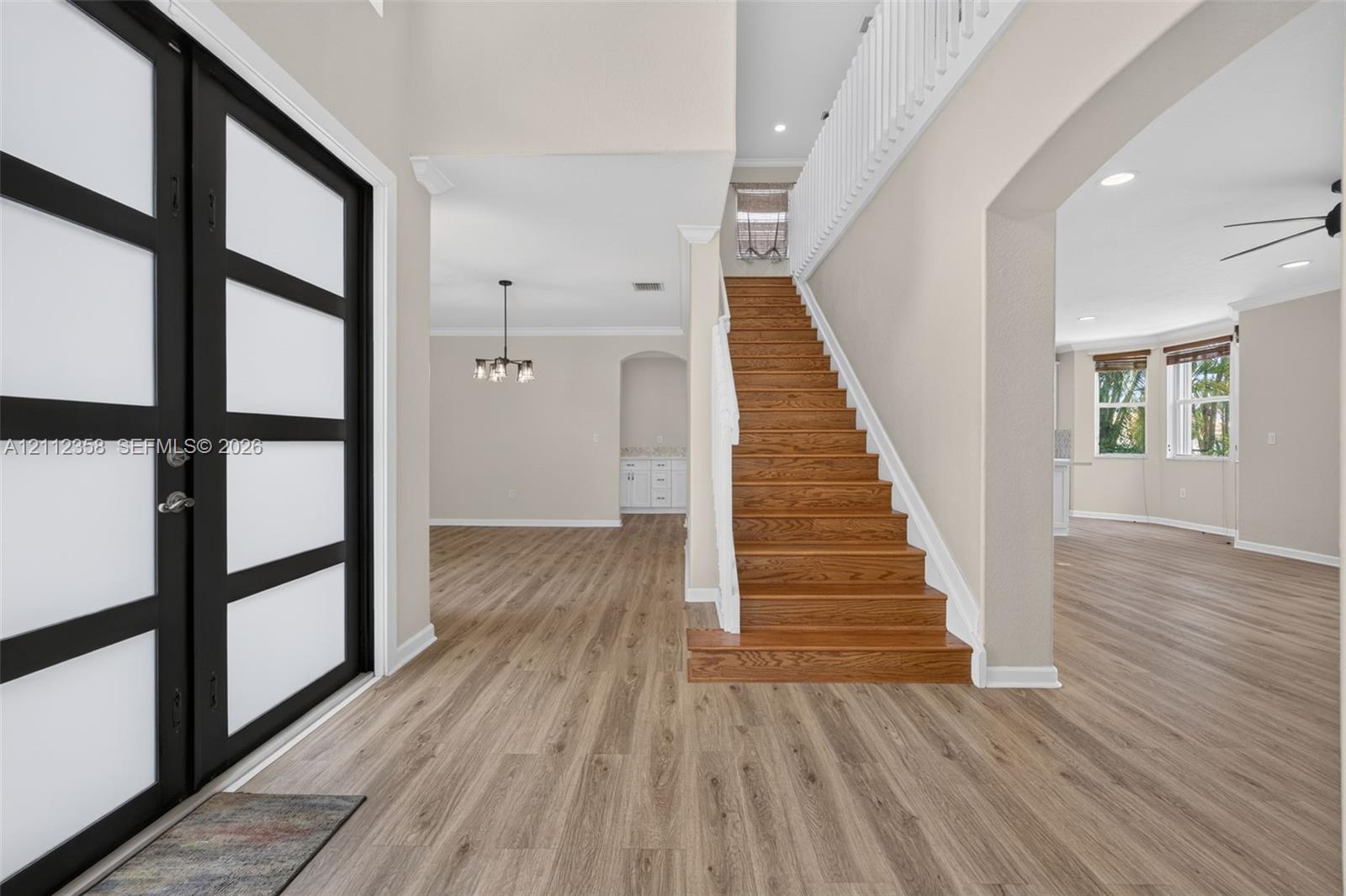 Double entry with frosted glass panels, wood-finish flooring, staircase with natural wood treads, and white balustrade