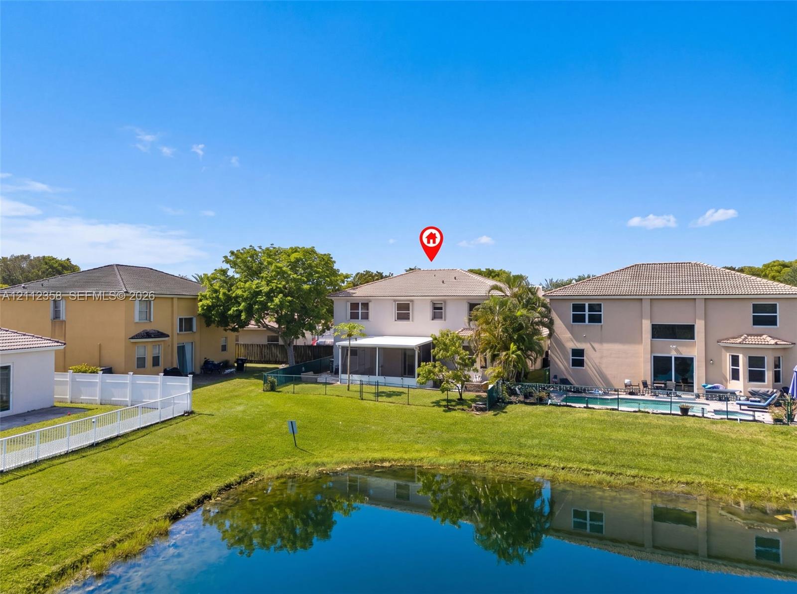 Two-story residence featuring a screened-in lanai, tile roof, and waterfront positioning overlooking a retention pond