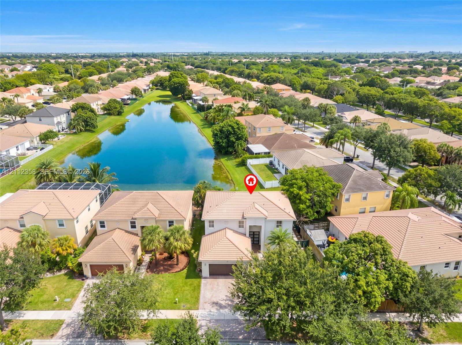 Aerial perspective featuring a two-story residence with a concrete tile roof, a multi-car garage, and proximity to a water feature