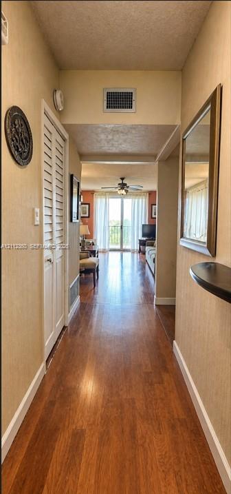 Hallway featuring wood-finish flooring, louvered bi-fold closet doors, and a built-in wall-mounted shelf
