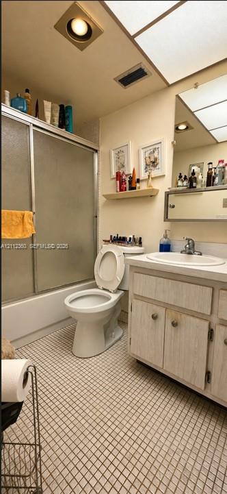 Bathroom featuring a tub-shower combination with sliding glass doors, a vanity with an integrated basin, a wall-mounted medicine cabinet, recessed lighting, and tiled flooring