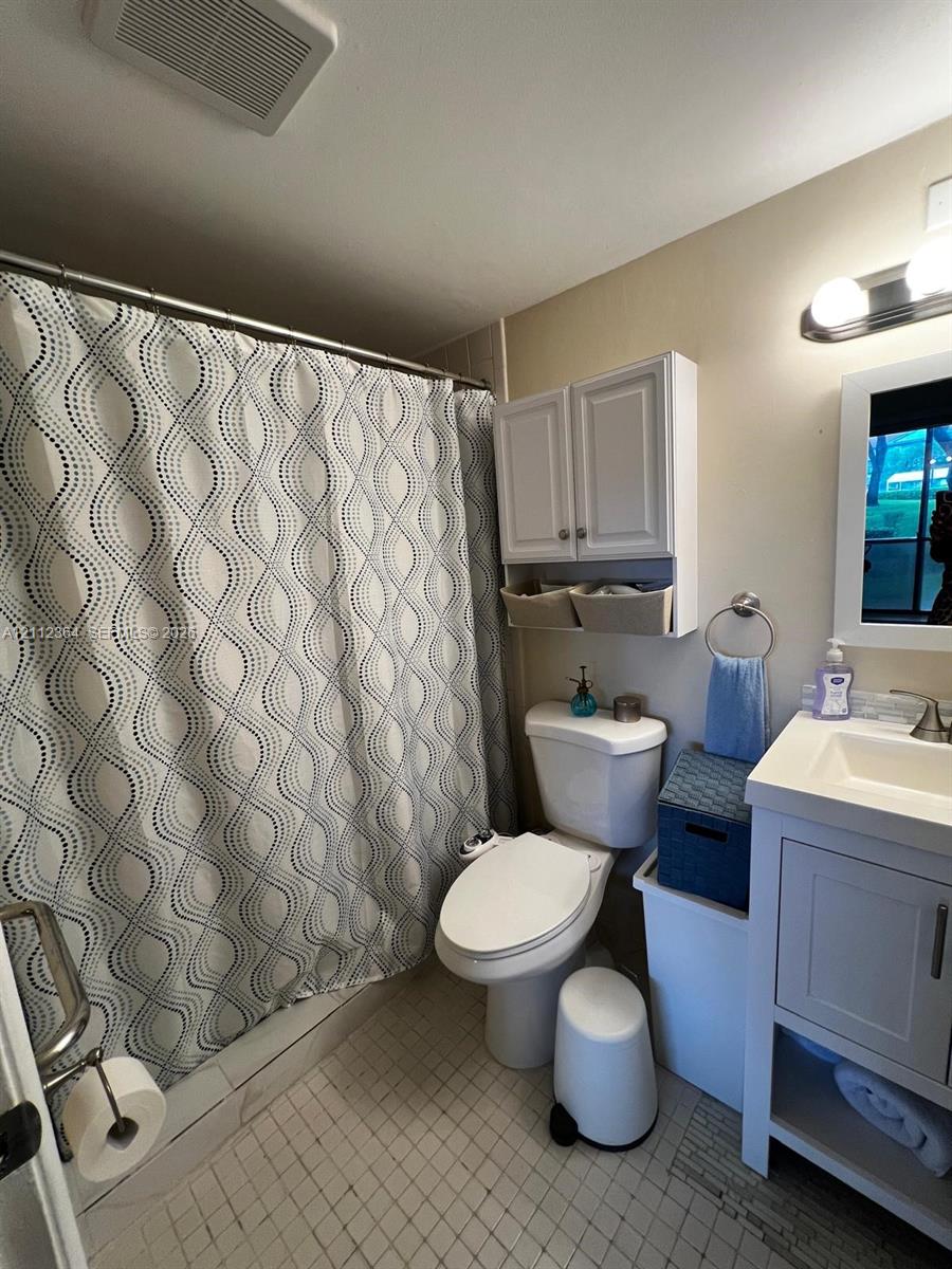 Bathroom featuring a vanity with integrated sink, wall-mounted upper cabinetry, tub-shower combination, tiled flooring, and multi-bulb light fixture